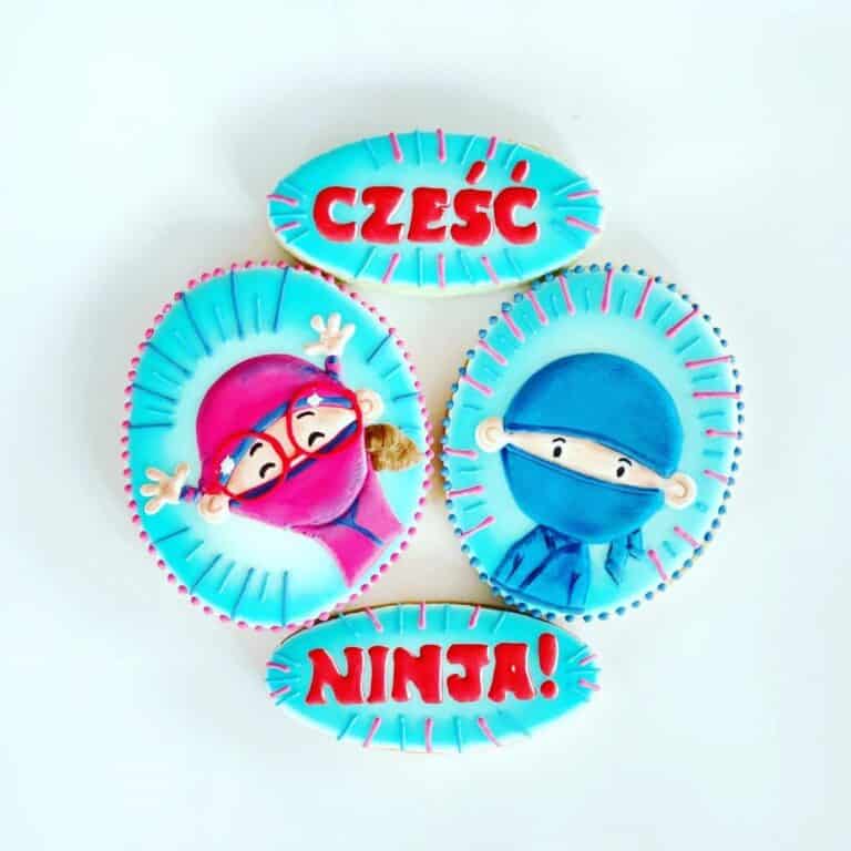 Cztery ciasteczka, w tym dwa z napisami "cześć", "ninja" oraz dwa z postaciami z kreskówki.